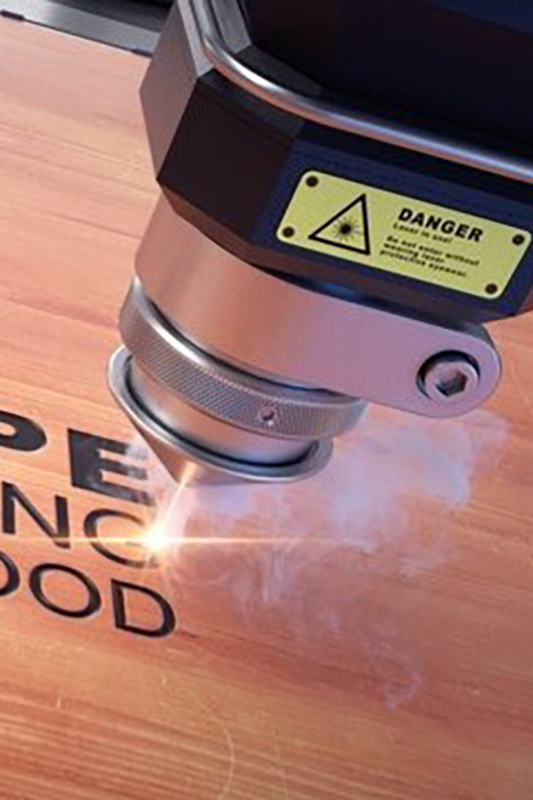 a laser engraving machine burning a design into a wooden surface