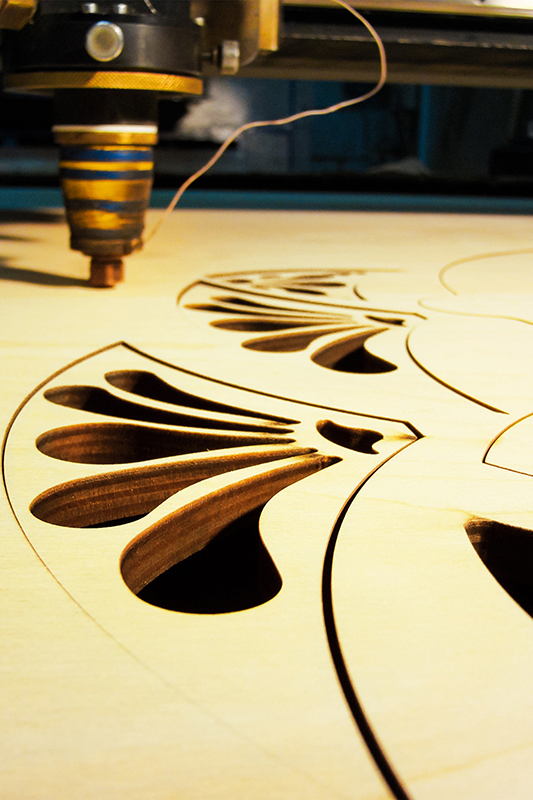 Laser machine engraving a design onto some wood