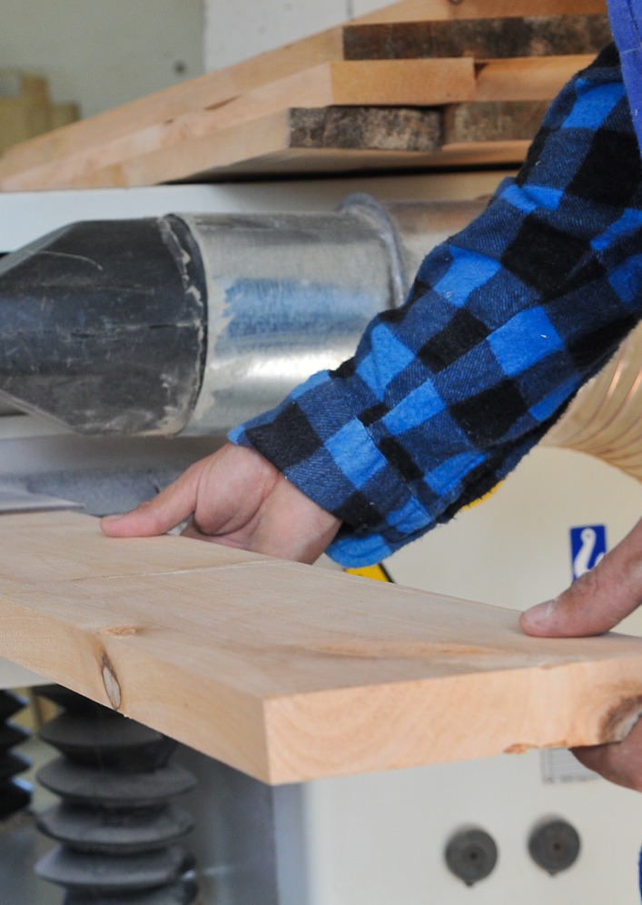 a man holding a plank of wood and cutting it in a swamill