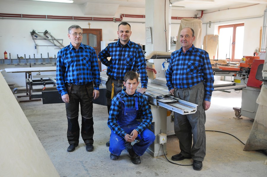 factory workers wearing matching blue checked shirts standing in front of their equipment