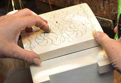 a man holding a wooden box with a decorated top