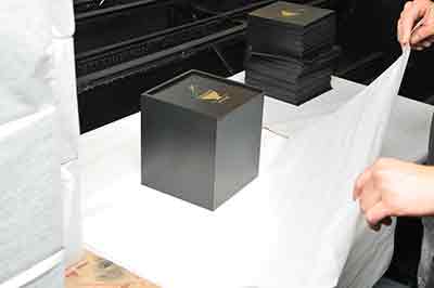 a person wrapping a wooden box in tissue paper