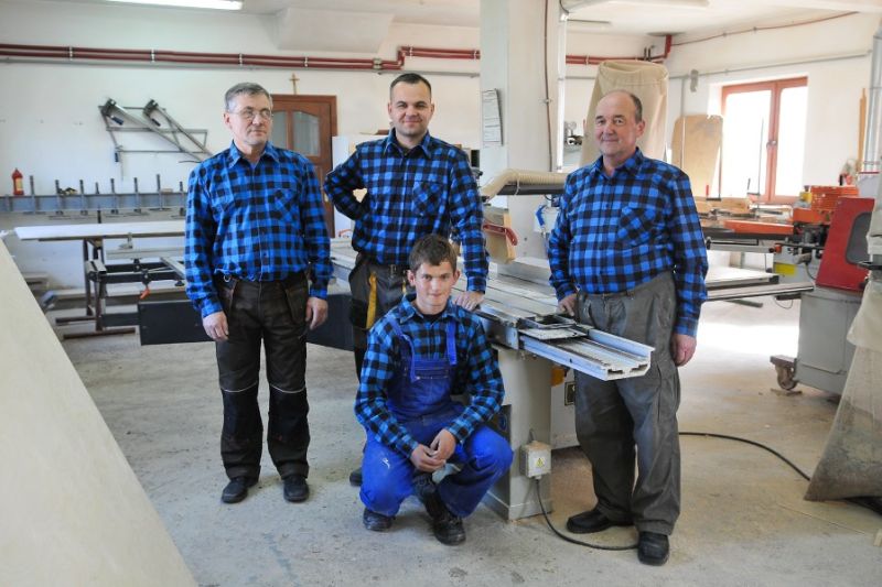 factory workers wearing matching blue checked shirts standing in front of their equipment
