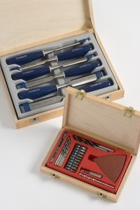 Wooden boxes with precision tools inside. The top box has blue-handled chisels, and the bottom displays assorted drill bits and a red triangular tool.