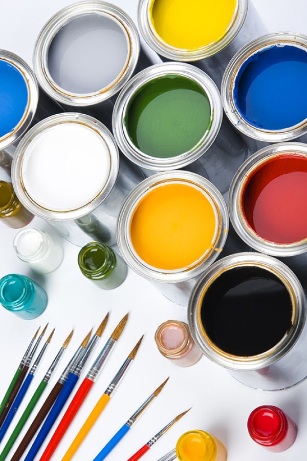 cans pf coloured paint with paintbrushes on a white background