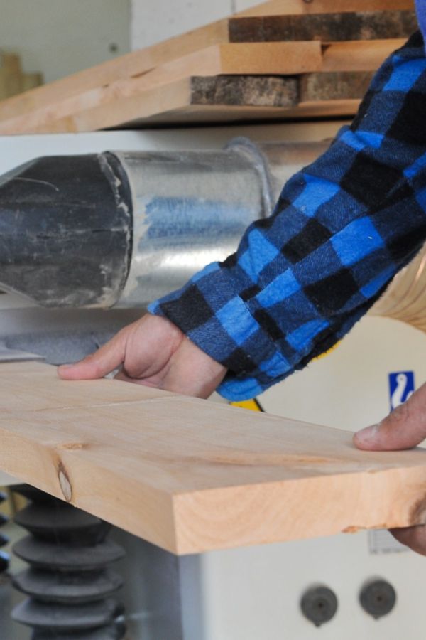 a man holding a plank of wood and cutting it in a swamill