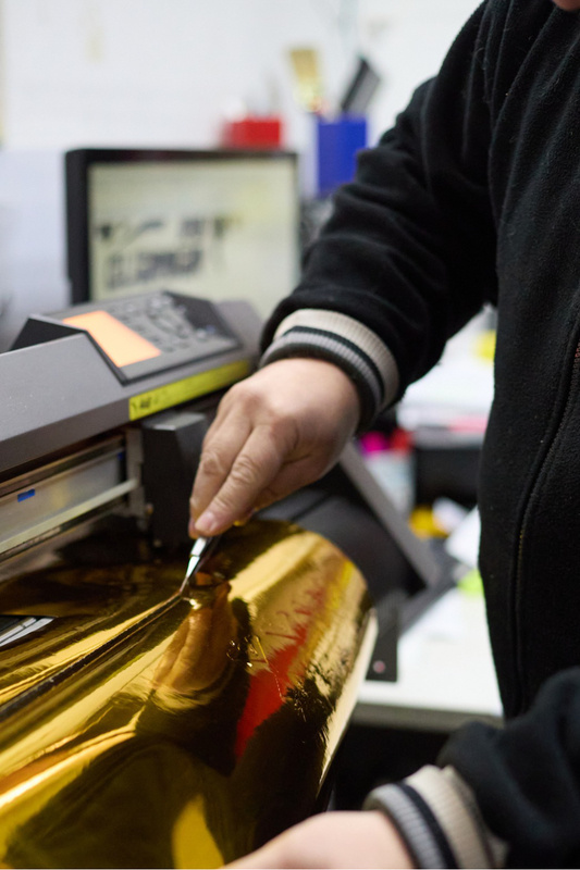 man cutting a roll of gold foil